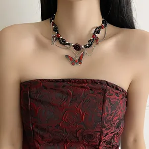 Detalle de un collar gótico oscuro con mariposas y colgantes de rosas de resina