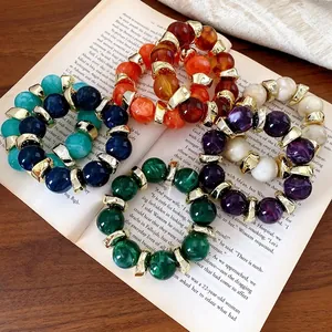 Set di bracciali in acrilico marmorizzato in vari colori con accenti dorati su un libro