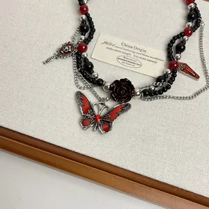 Primer plano de un collar gótico con dijes de mariposa roja, rosa y cuentas negras