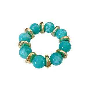 Elegante bracciale in perle di acrilico marmorizzato verde con distanziali dorati su bianco