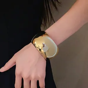 Bold chunky gold-plated cuff bracelet with mirror finish on female wrist