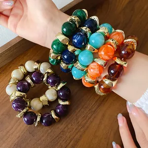 Dettaglio di braccialetti in perle di acrilico marmorizzato con distanziatori dorati