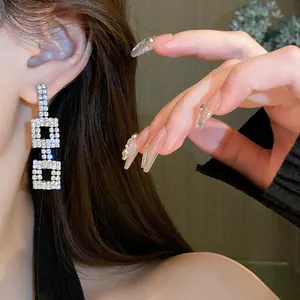 Primo piano di orecchini eleganti con nappa quadrata e strass scintillanti