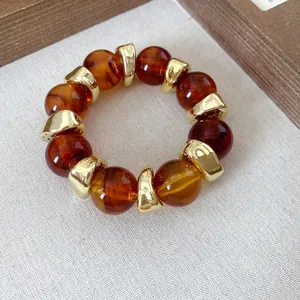 Vista dettagliata del bracciale con perle in acrilico ambra e distanziatori dorati