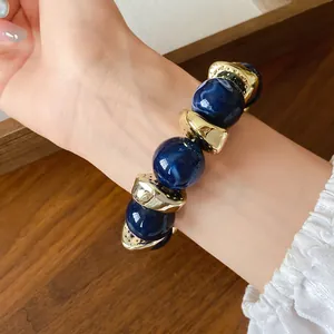 Vista dettagliata di un bracciale in perle acriliche blu marmorizzate con distanziatori dorati