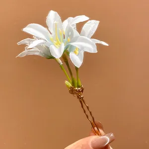 Close-up of white fabric lily flower hair stick with realistic water droplets