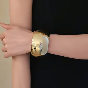 Detail of wide polished gold cuff bracelet worn on wrist for an elegant look