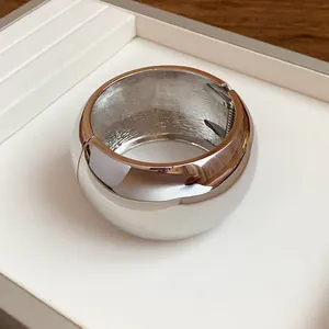 Close-up of chunky polished silver metal cuff bracelet with a spring hinge detail