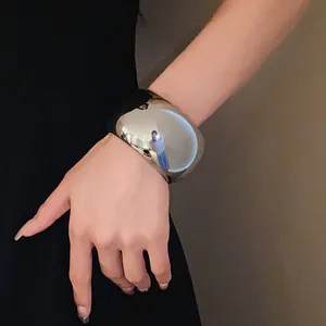 Detailed view of a minimalist silver metallic wide cuff bracelet on a female wrist