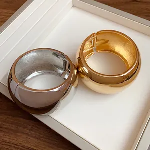 Detail view of wide metallic dome bangles with polished gold and silver finishes