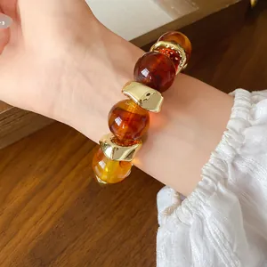 Vista dettagliata di un bracciale in acrilico marmorizzato con grosse perle dorate