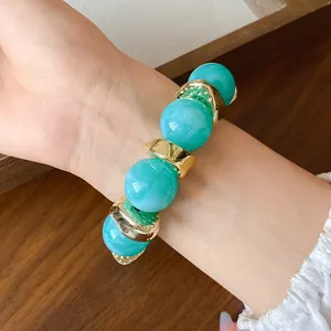 Dettaglio del bracciale con perle acriliche turchesi venate e distanziatori dorati