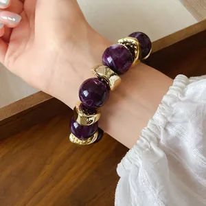 Vista dettagliata di un bracciale con perle acriliche viola marmorizzate e inserti oro