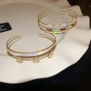 Close-up of elegant double-layered gold bracelets with zircon four-leaf clover charms
