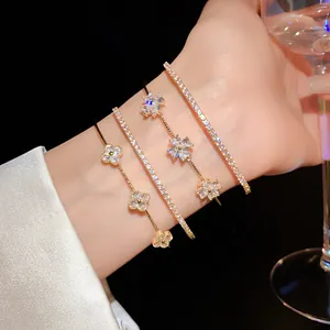 Close-up of elegant gold bracelets with zircon flower and clover motifs on wrist