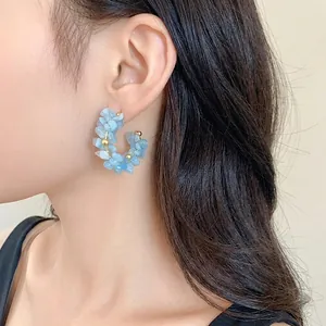 Eleganti orecchini a cerchio in scaglie di acquamarina blu con dettagli dorati su modella