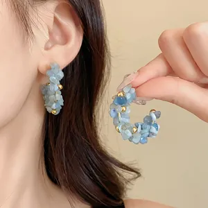 Primo piano di eleganti orecchini a cerchio con scaglie di acquamarina e perle oro