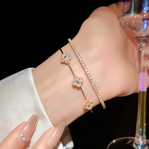 Close-up view of a luxury gold zircon clover bracelet and sparkling tennis bracelet set