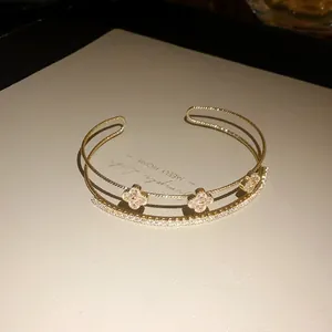 Detailed view of an elegant triple-layer gold bracelet with sparkling zircon clover charms