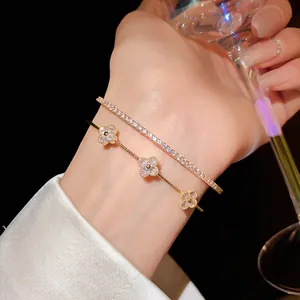 Close-up of elegant gold zircon four-leaf clover bracelet set worn with crystal glass