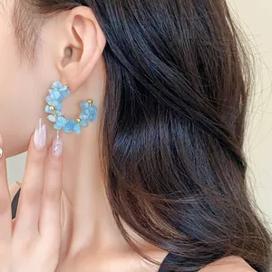 Primo piano di eleganti orecchini a cerchio a C con pietre preziose azzurre su una modella