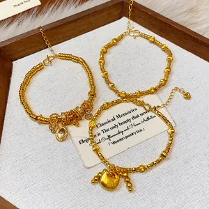 Detailed view of three gold-plated bracelets with lock and stone charms in a wooden tray