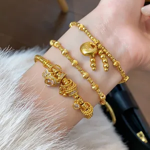 Close-up of gold-plated bracelets featuring a lucky charm lock and intricate beads