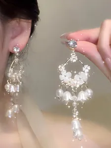 Macro view of French style flower and pearl dangle earrings with silver needles