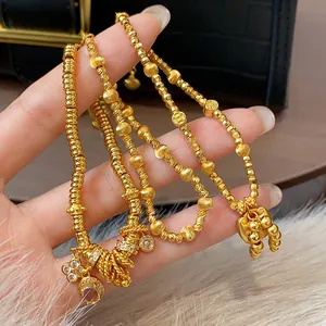 Close-up of gold-plated beaded bracelets featuring lock charms and crystal details.