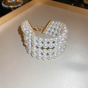 Elegant four-strand pearl bracelet with 18k gold-plated metal bars and adjustable clasp.