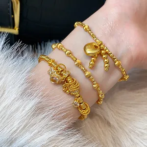 Close-up of elegant gold-plated beaded bracelets featuring a small lock charm and crystals