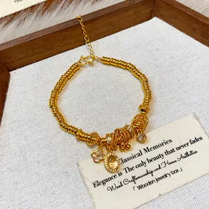 Detail shot of a gold-plated beaded bracelet with elegant flower and stone charms.