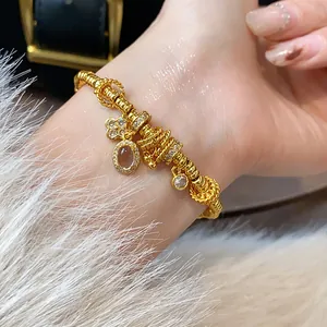 Close-up of gold-plated charm bracelet with sparkling gems on a female wrist