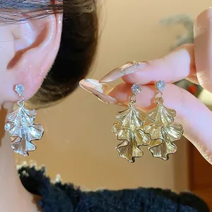 Detail view of gold and silver wrinkled leaf earrings with sparkling rhinestone accents.