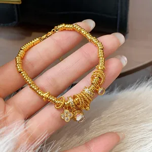Detailed close-up of a gold-plated beaded bracelet with elegant clover charm on hand.