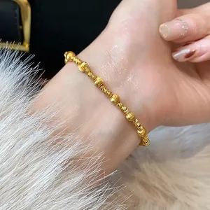 Detailed macro view of a minimalist gold-plated beaded bracelet on a woman's wrist