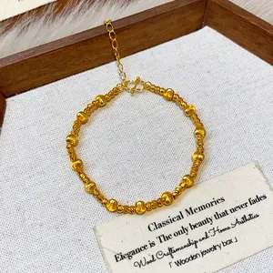 Close-up of gold-plated beaded bracelet with elegant textured finish on a rustic display.