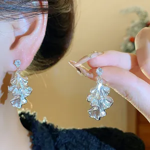 Detailed view of elegant silver wrinkled leaf earrings with a sparkling zircon stud