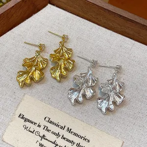 Detailed view of ruffled leaf design earrings in both gold and silver tone finishes.