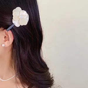 Elegant white camellia flower hair clip with pearl detail worn by an Asian model.