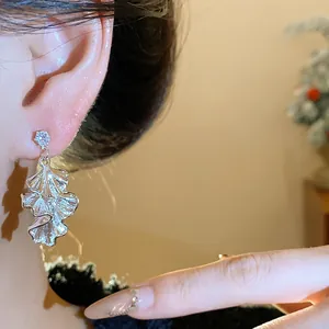 Close-up view of elegant pleated silver leaf earring featuring a sparkling zircon stud detail