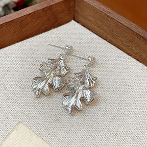 Detailed macro view of elegant silver leaf-shaped earrings featuring a unique wrinkled texture