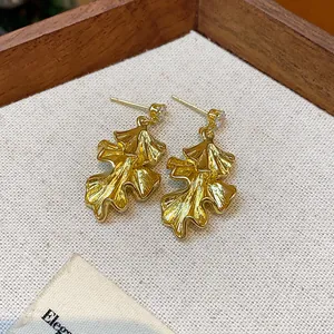 Macro view of elegant gold-toned wrinkled leaf earrings with sparkling crystal studs