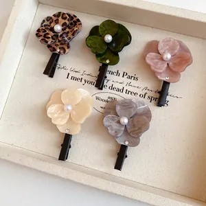 Close-up of five assorted floral hair clips with pearls and rhinestones in a tray