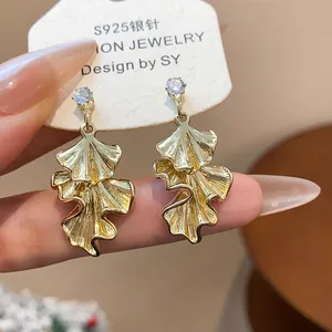 Macro detail of pleated gold-colored leaf earrings featuring S925 silver needles.