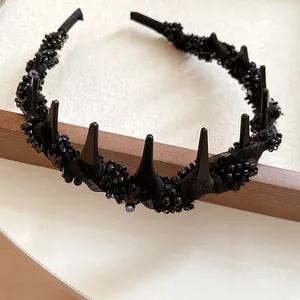 Detail view of a black mesh wrapped headband with glass beads and gothic spikes.