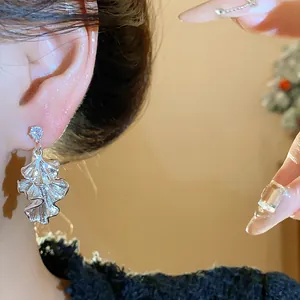 Close-up of silver crumpled leaf earrings worn on ear with elegant zircon detail