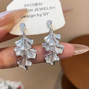 Close-up detail of textured silver leaf drop earrings with sparkling crystal studs.