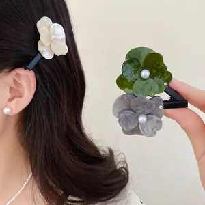 Close-up of elegant acetate floral hair clips with pearl detail shown on a model