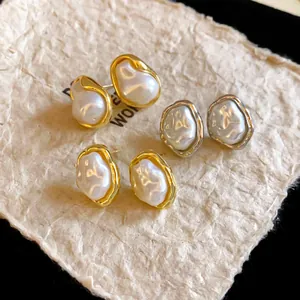 Close-up of irregular faux pearl stud earrings with gold and silver metal edges